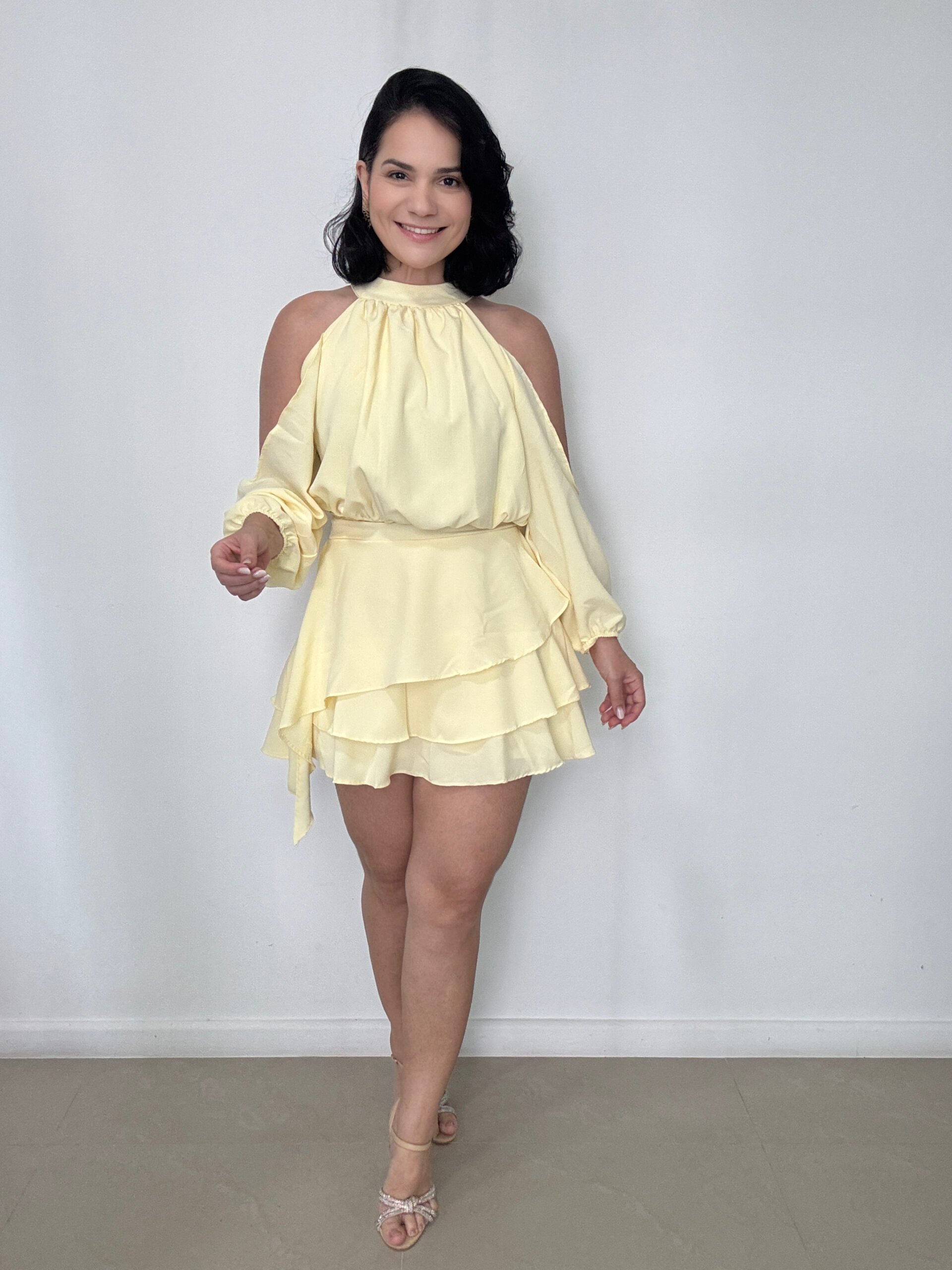 Macaquinho Maitê Amarelo Manteiga em Crepe Vegas com gola alta, ombros vazados e modelagem elegante.